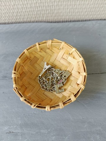 Handgemaakt bamboe offerschaaltje van bovenaf gefotografeerd met een zilveren armband en bedeltjes erin als sieradenhouder