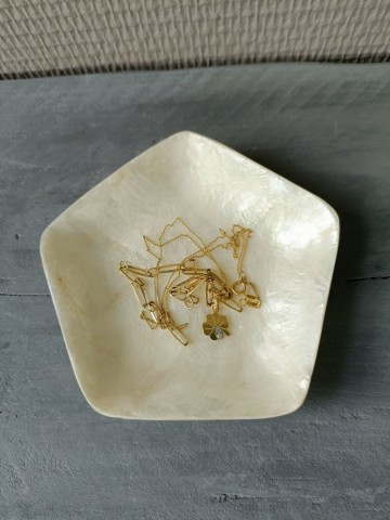 Vijfhoekig Capiz schelpen schaaltje van bovenaf gefotografeerd met een elegant gouden armbandje erin