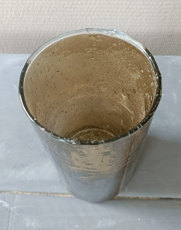 Detail van de geribbelde halsopening van een bruine glazen vaas met parelmoerglans