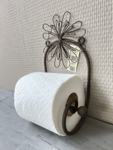 Zijaanzicht van de industriële metalen toiletrolhouder met een geplaatste toiletrol
