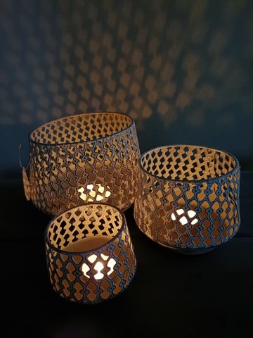 Set van drie windlichten in rustiek wit-grijs, brandend, recht van voren gefotografeerd.