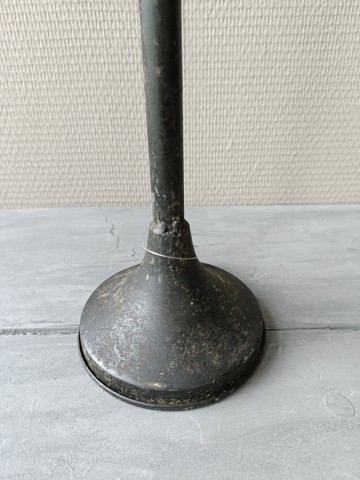 Detail van de ronde metalen voet van de vintage zwarte kandelaar met verweerde bruine en grijze accenten