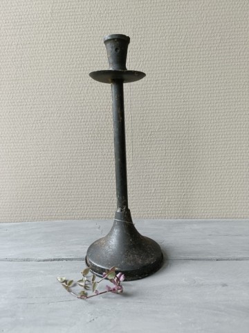 Vintage metalen kandelaar in zwart met een doorleefde afwerking op een stoere houten ondergrond