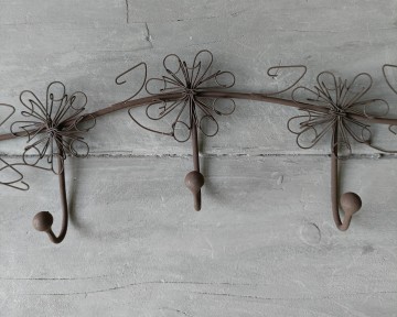 Detailopname van stoer zink, draadijzer en bloemendetails van de wandhaak
